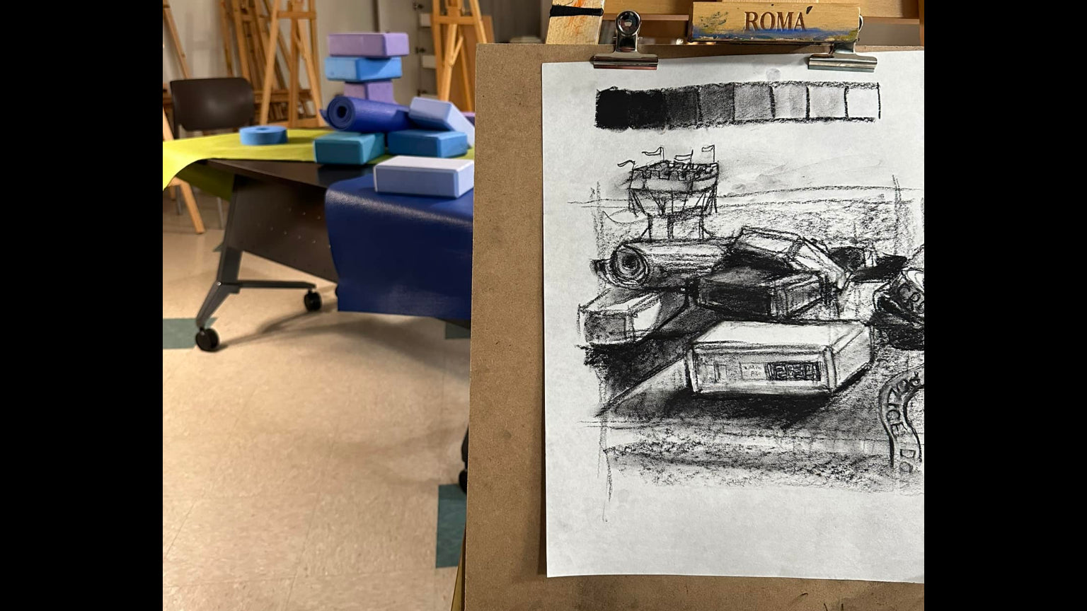 Art studio with easels and a drawing of a room on a piece of paper.
