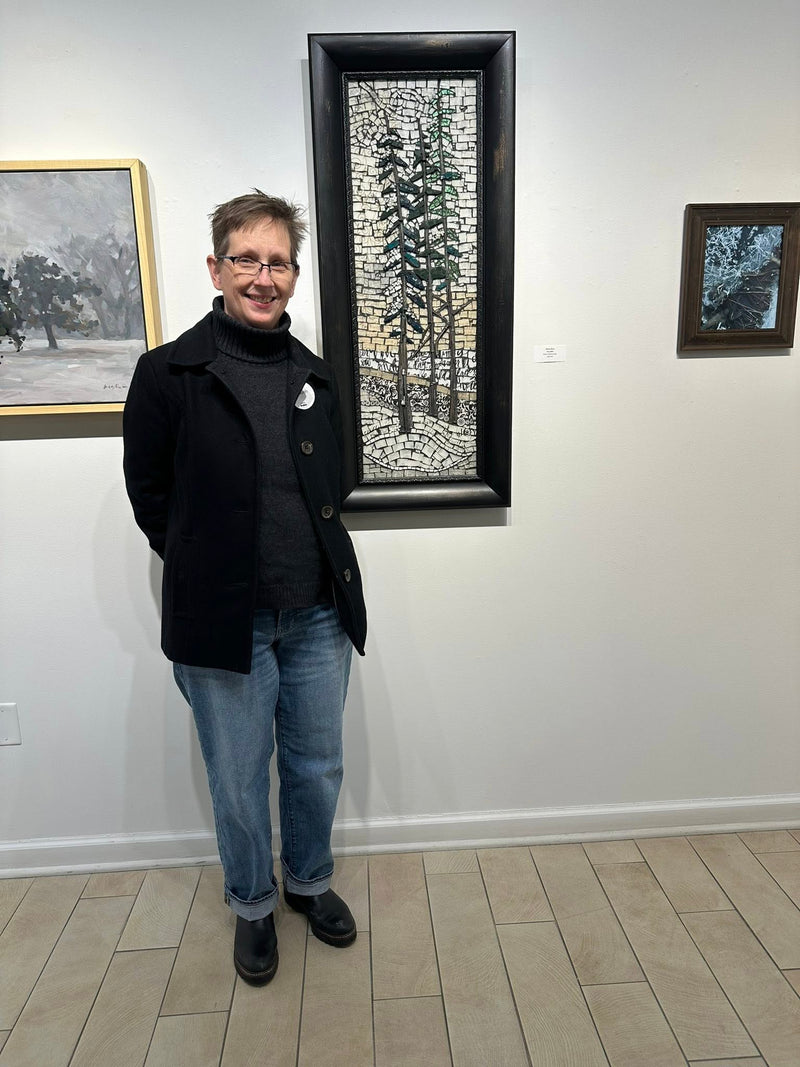 Person standing in front of a wall with framed artworks in an art gallery.