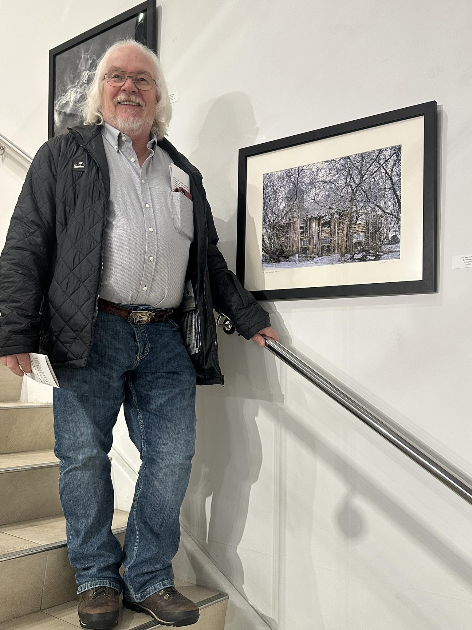 Man standing on a staircase next to a framed photograph of a snowy scene