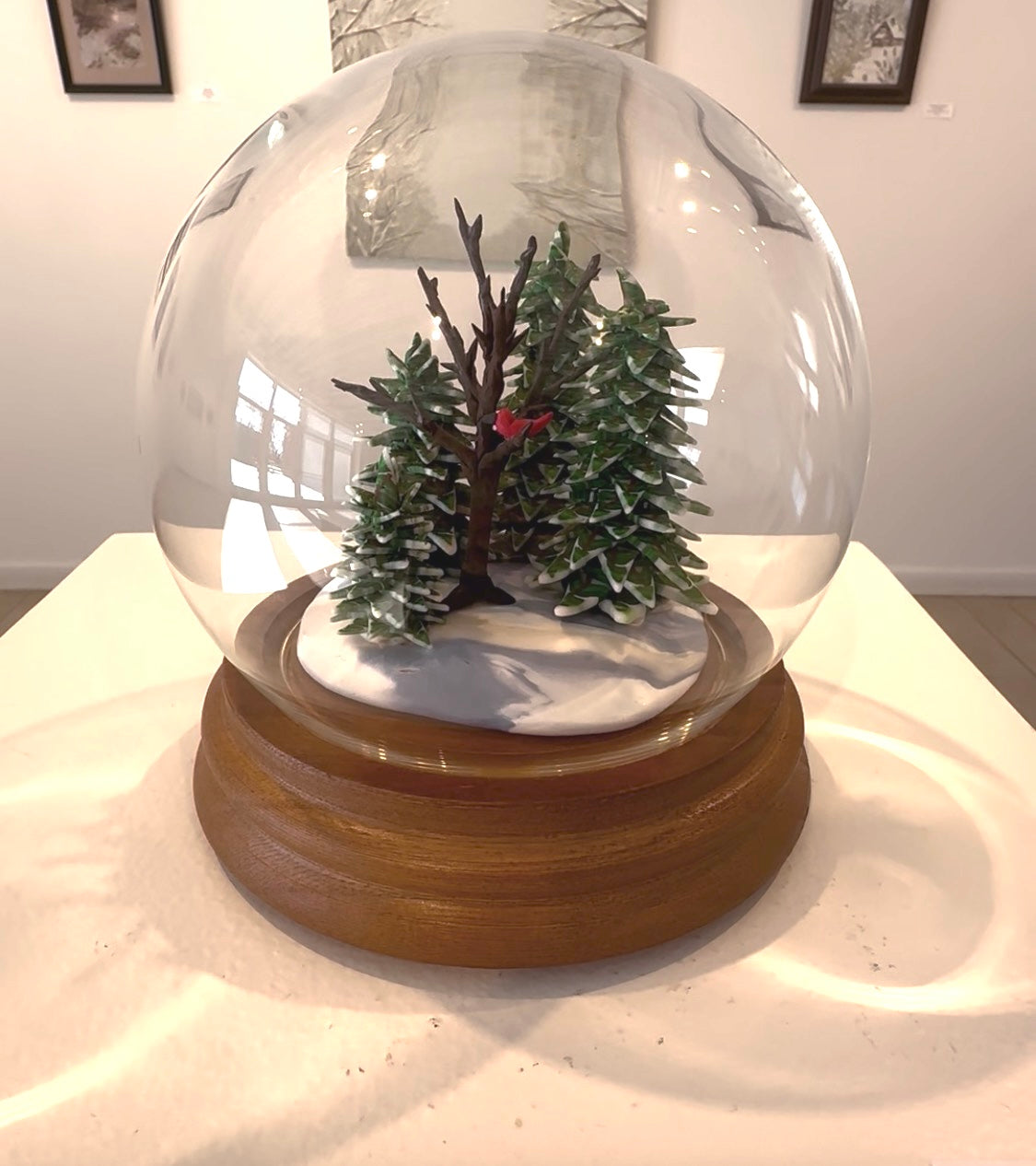 Snow globe with a small tree and snow on a wooden base