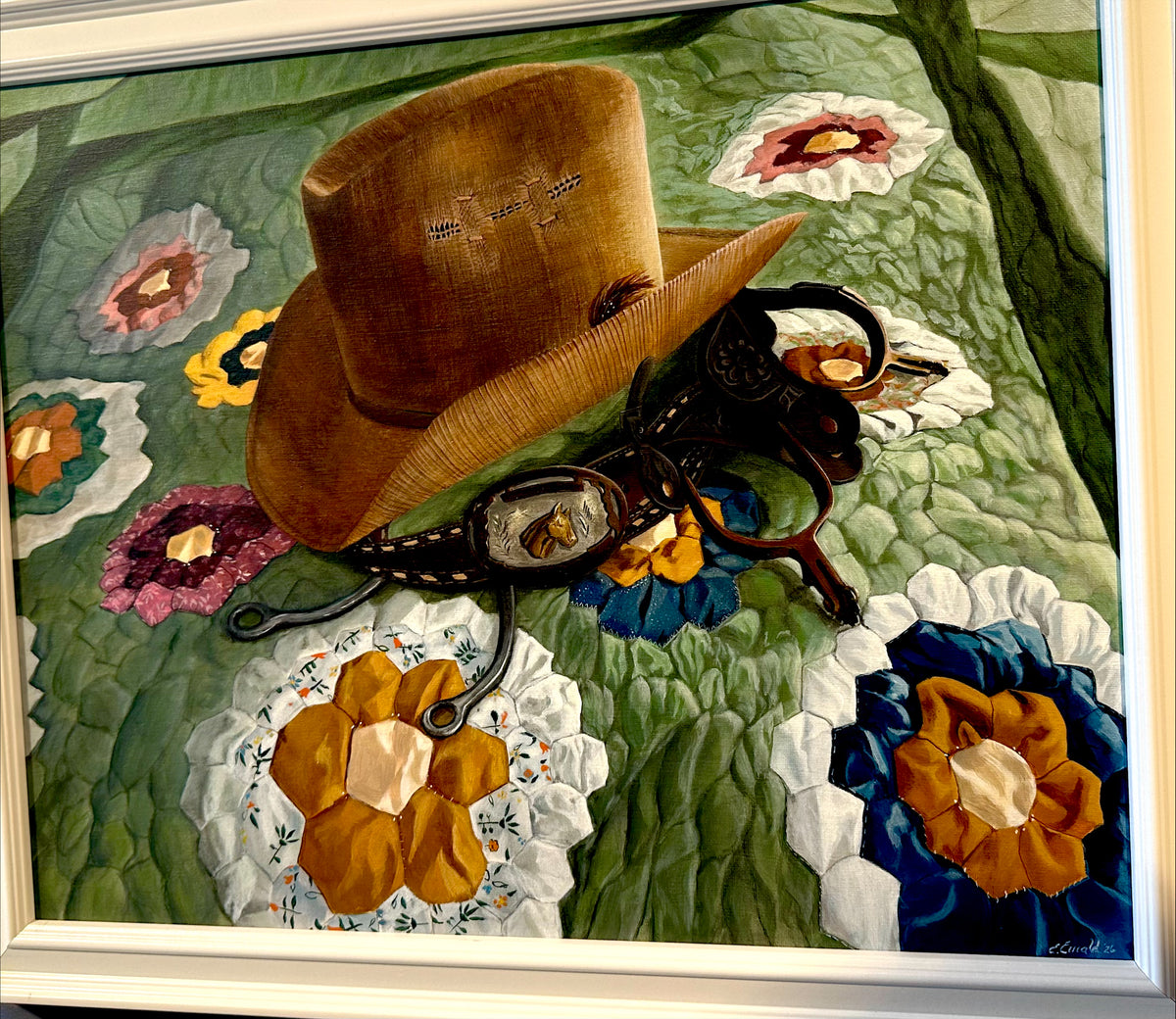 Brown cowboy hat and belt on a floral quilt with a white frame.