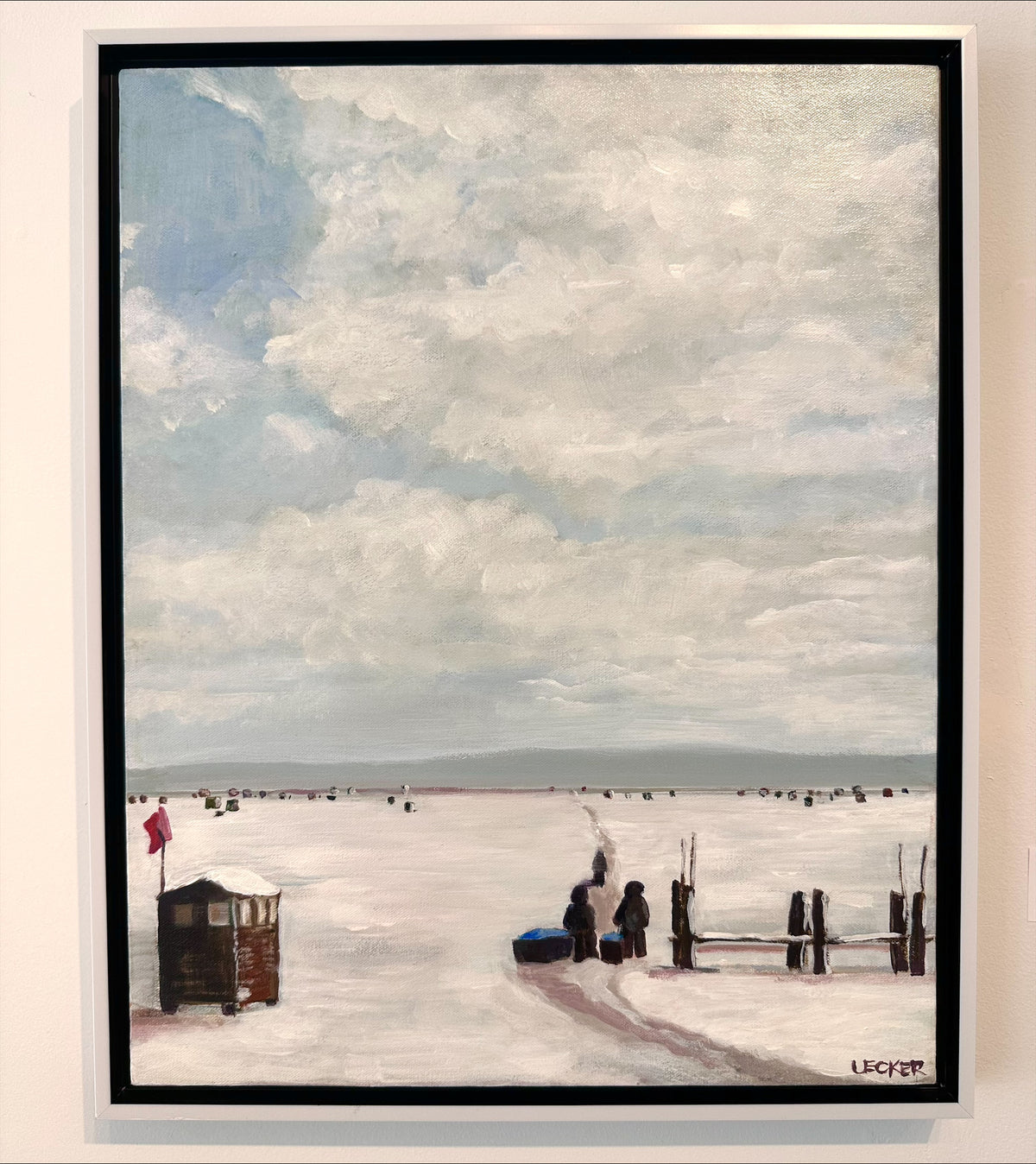 Framed artwork of a beach scene with people and a lifeguard stand under a cloudy sky.